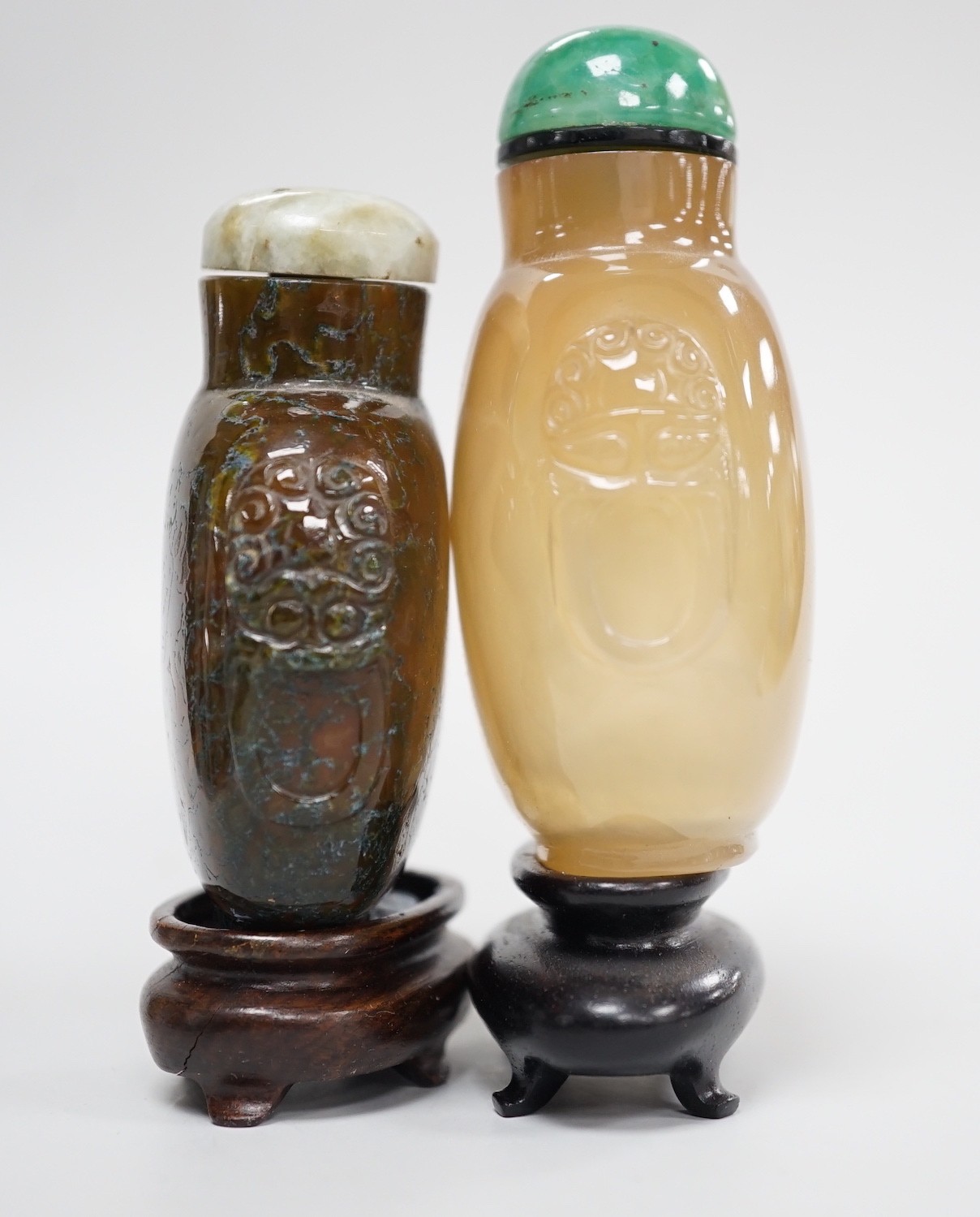 A Chinese honey coloured agate mask and ring handled snuff bottle and a dendritic chalcedony (moss agate) mask and ring handled snuff bottle, 5.7cm, both 1780-1880